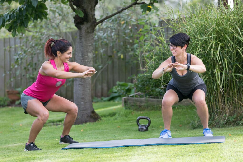two fit girls training with personal trainer in gym, attractive