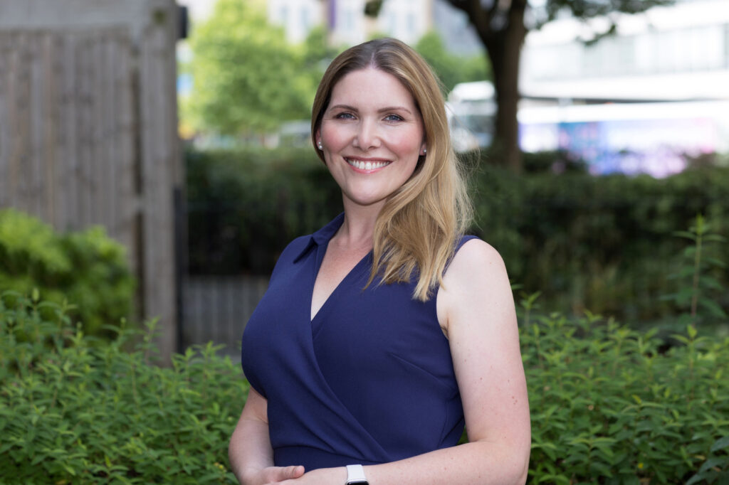 A smiling woman in a blue dress poses for a Croydon headshot photographer