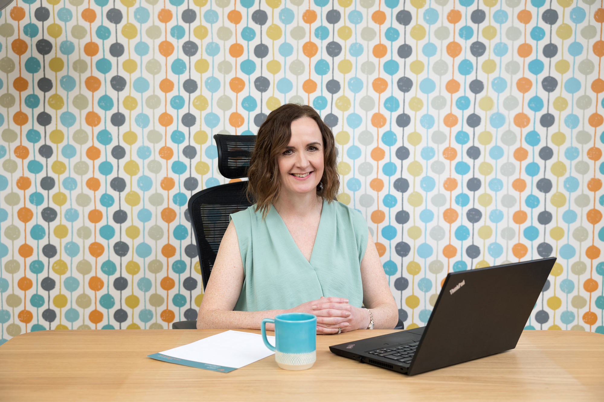 A woman at her desk in front of a spotty wall during her Croydon personal branding photography shoot