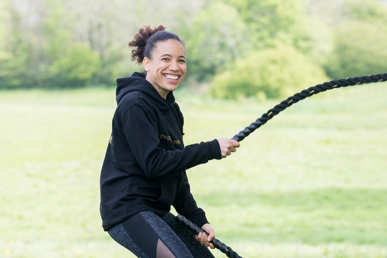 A woman exercises with battle ropes in the park during a personal branding health & fitness photography shoot