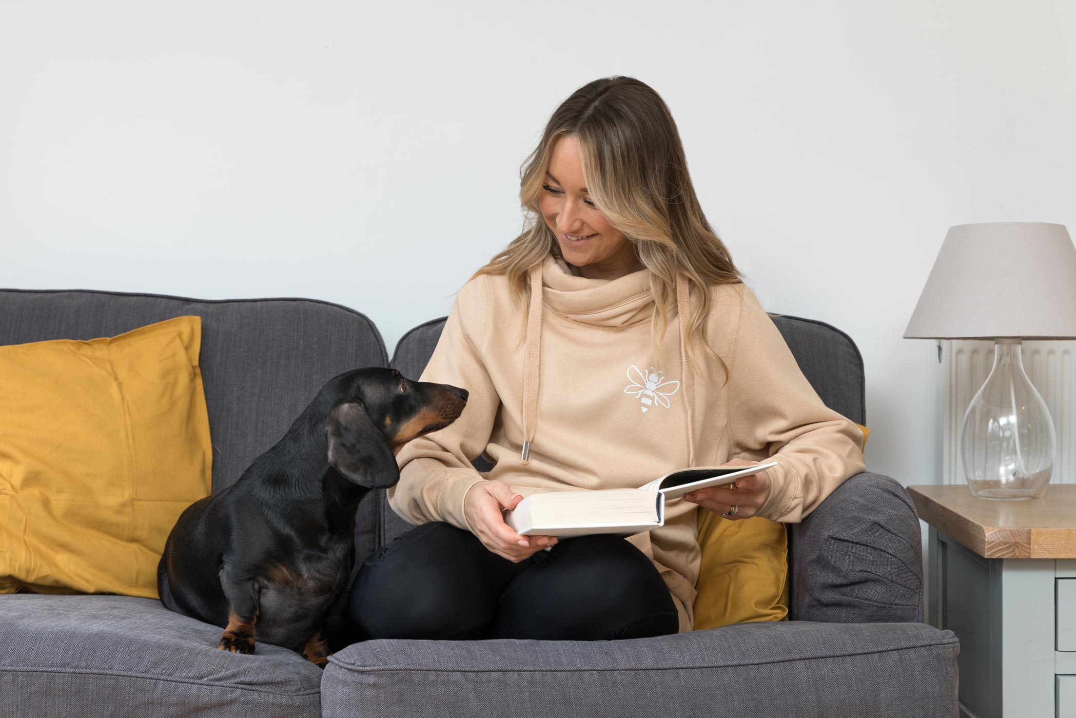 A woman sits on a sofa reading with her dog during her personal branding photography shoot in Surrey
