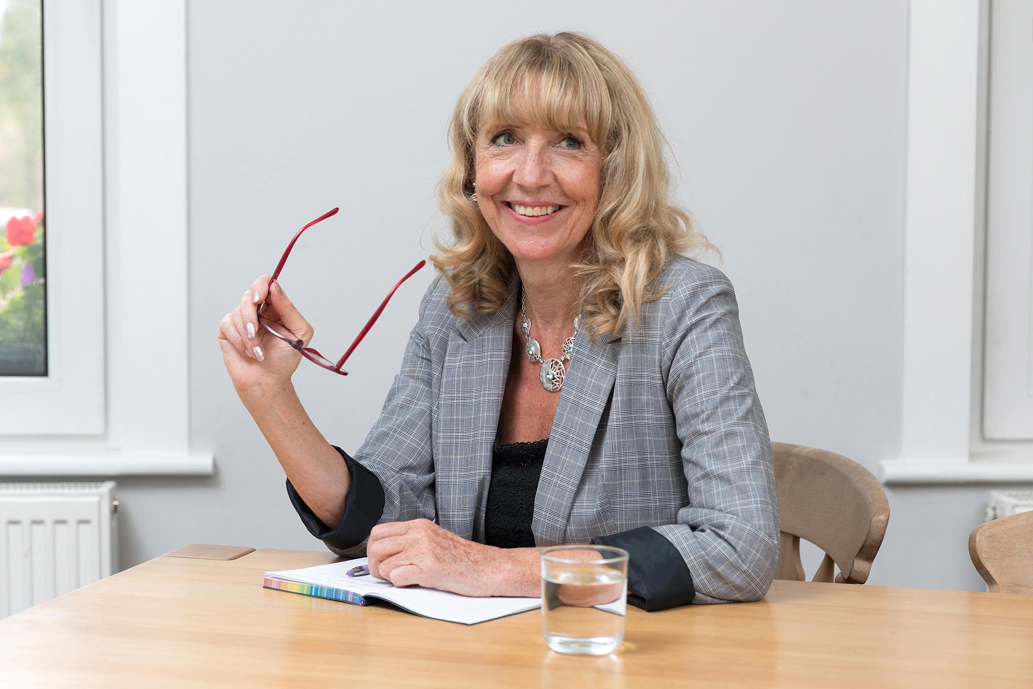 A business woman holds her glasses & smiles. Personal branding photography in Croydon, London & Surrey