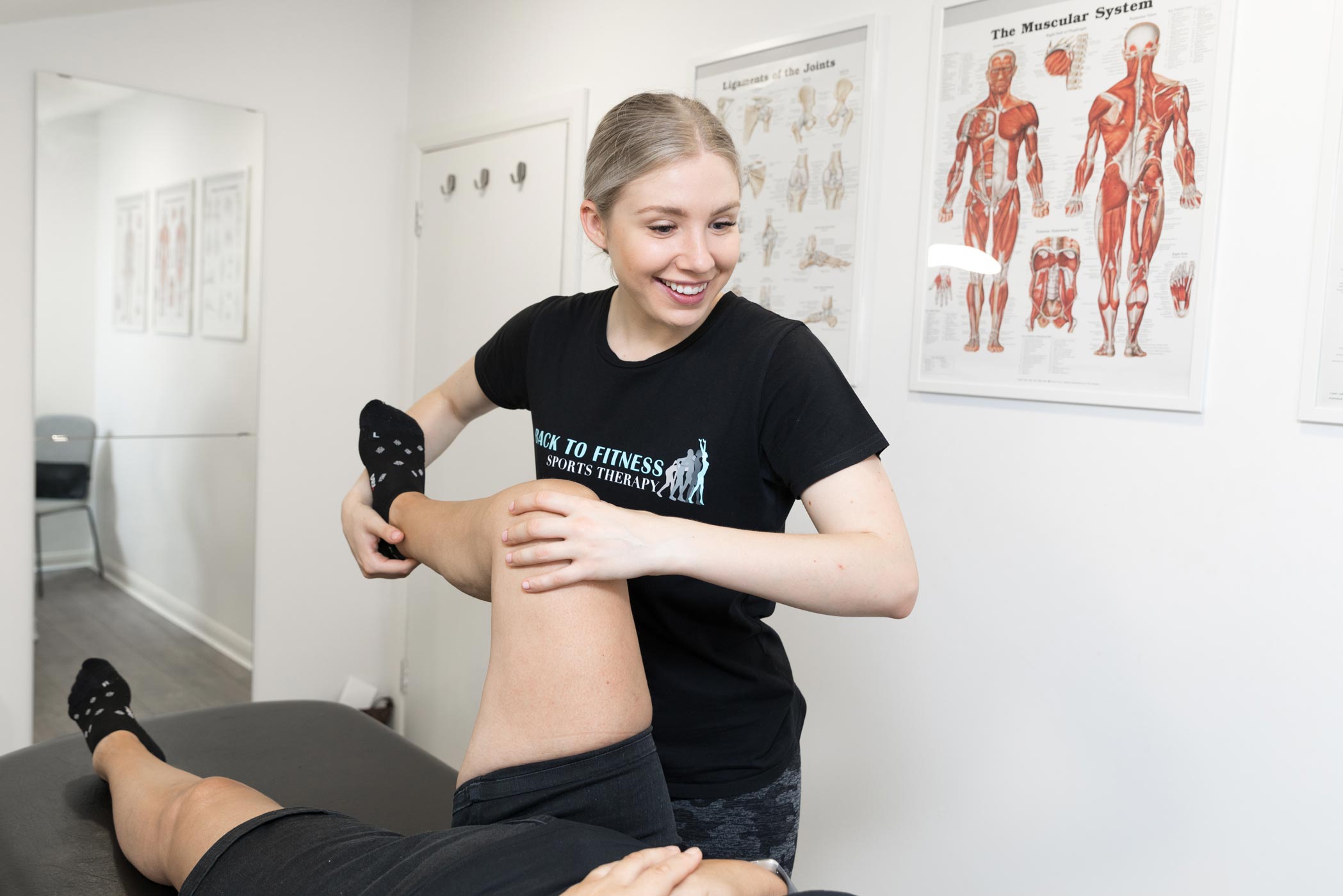 A sports massage therapist works with a patient in her Croydon clinic as part of a London health & fitness personal branding photography shoot