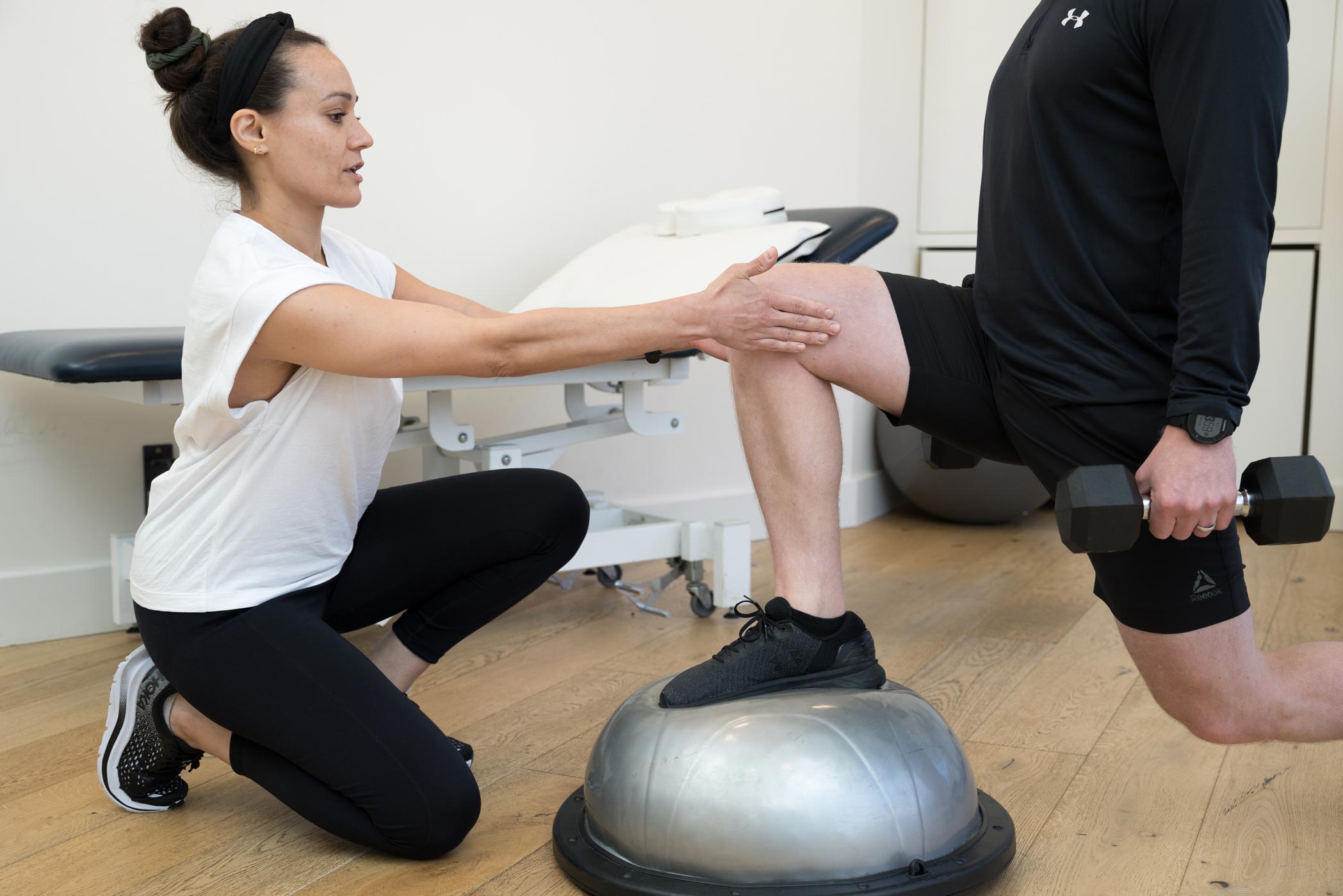 A physiotherapist treats a clients knee injury at a clinic in Balham, London during a health and fitness personal branding photography shoot
