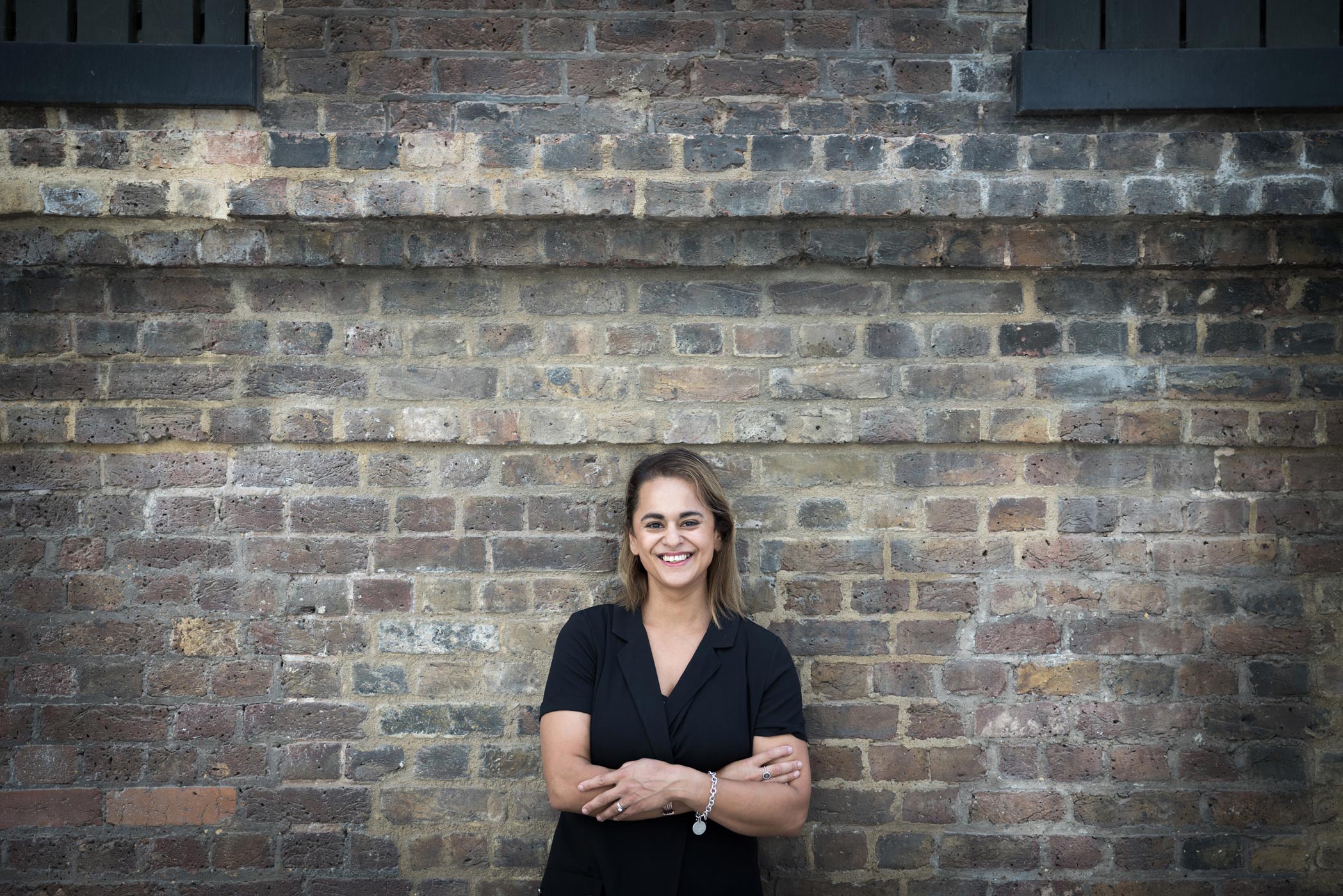 A business woman leans up against a wall in Coal Drops Yard in Kings Cross, London for a portrait at her personal branding photography shoot by Croydon photographer Ally