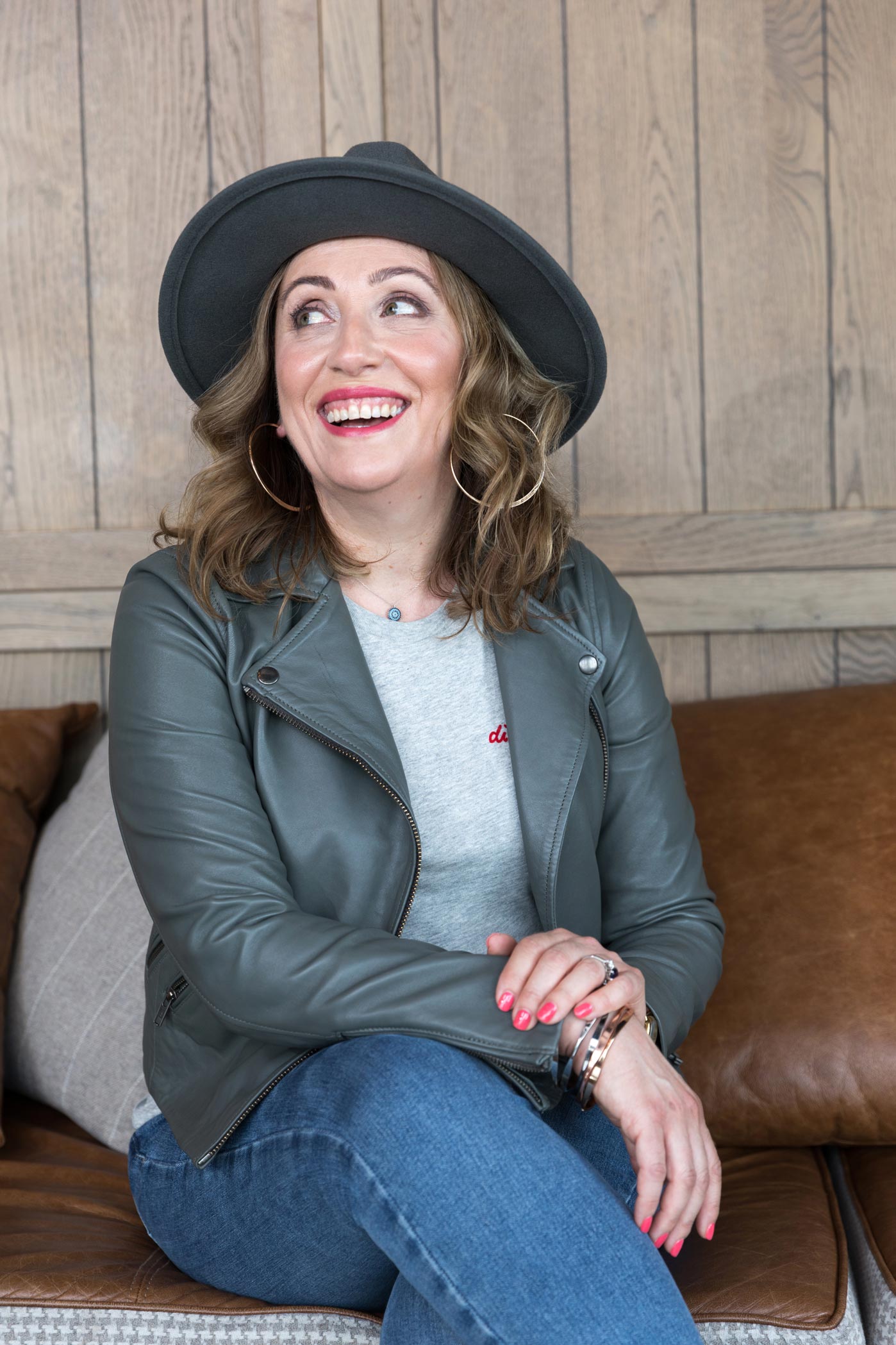 A woman in a hat laughs at a personal branding photoshoot in London