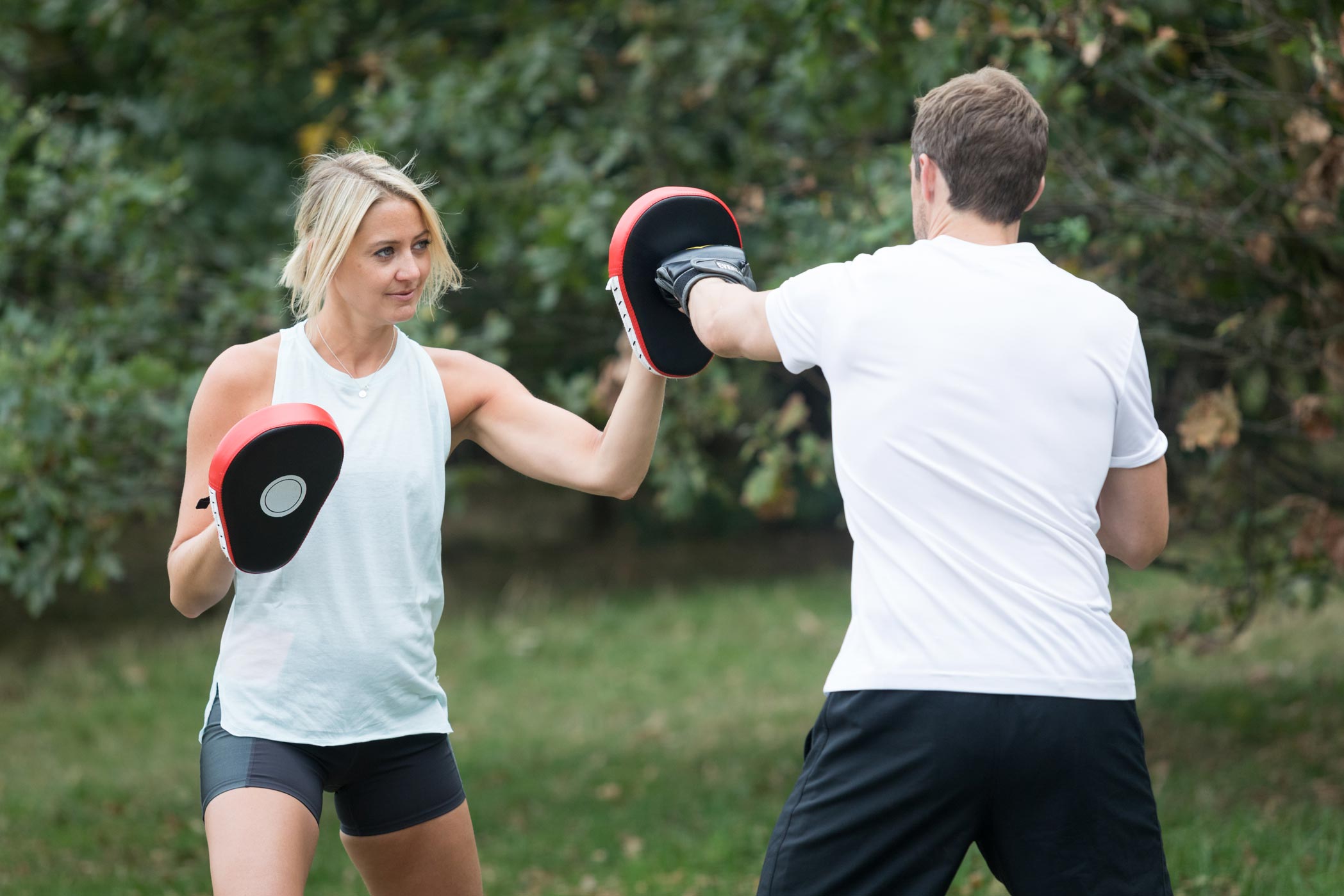 A female personal trainer practices boxing with a client during a health & fitness personal branding photography shoot in Croydon, London