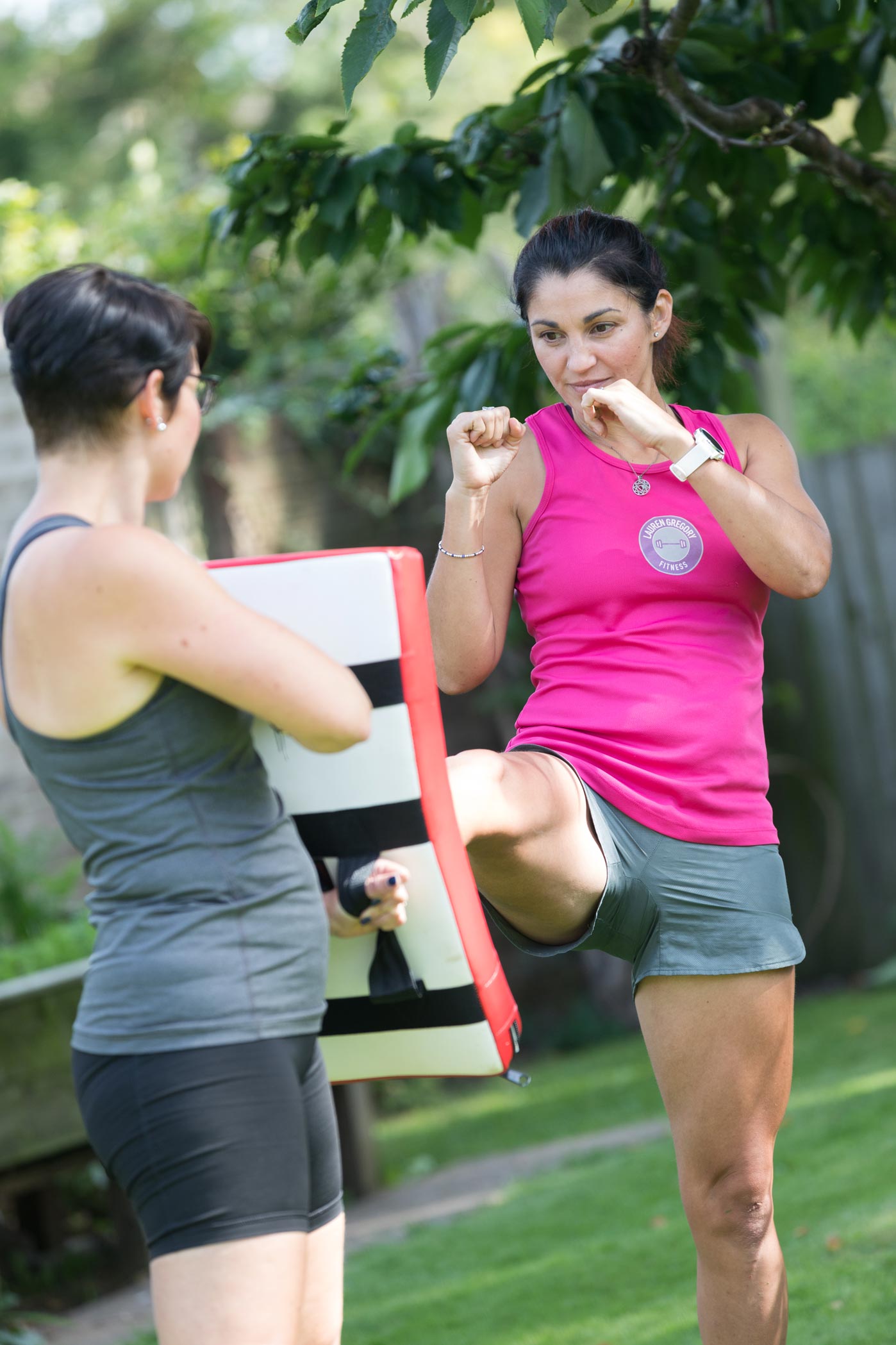 A female personal trainer practices kickboxing with a client during a health & fitness personal branding photography shoot in London