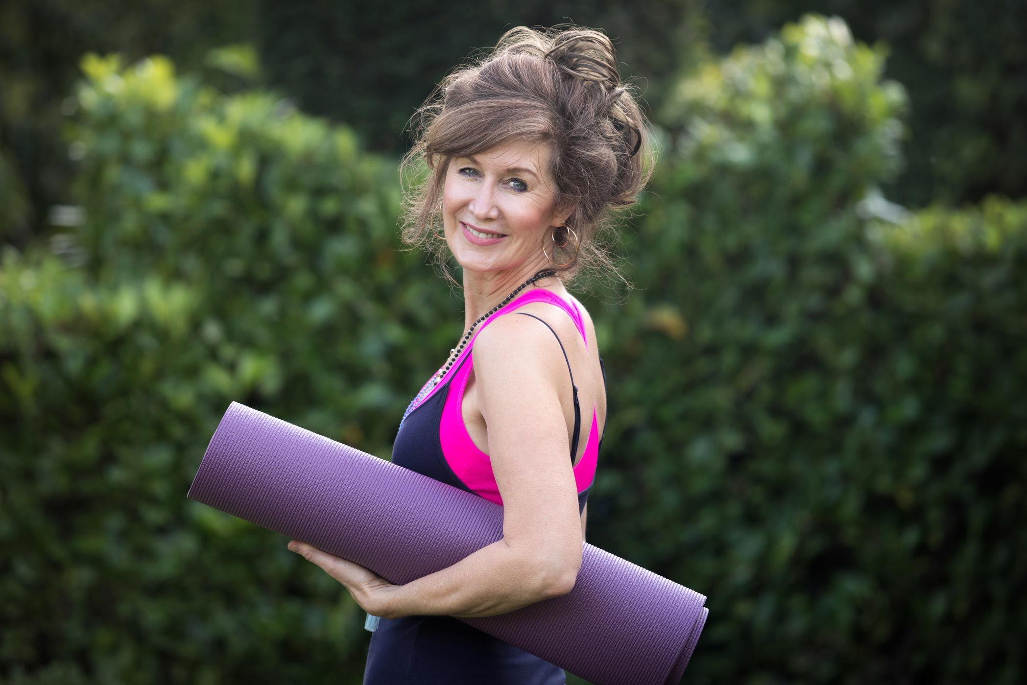 A female yoga teacher holds her mat for a photo as part of her health & fitness personal branding photography shoot in Croydon, London