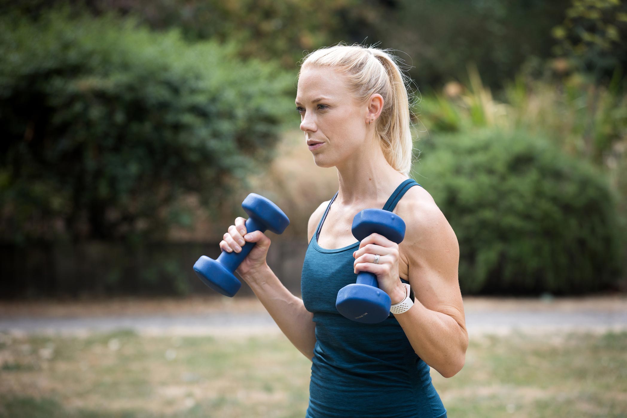 A female personal trainer holds dumbbells whilst posing for a photo as part of her health & fitness personal branding photography shoot in Croydon, London
