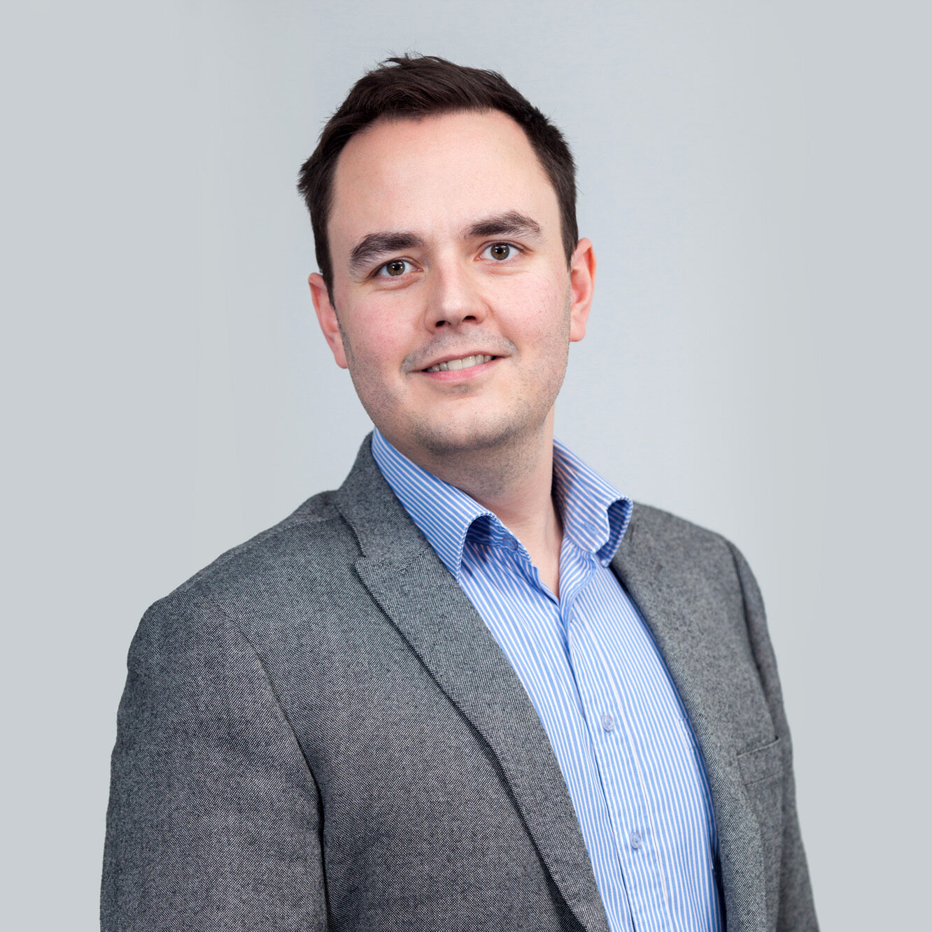 London corporate headshot photography; a business man in a grey suit against a plain grey background