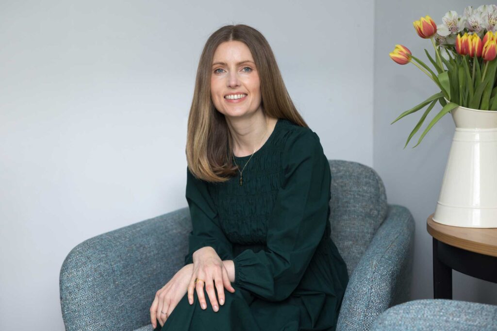 A photo of a lady in a green dress sitting on a blue armchair illustrating an article on how to brief a photographer