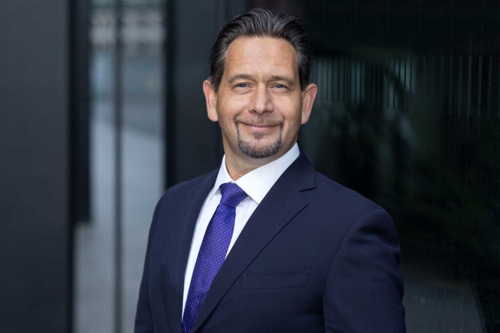 A man in a suit & tie poses for his corporate business headshot in Ruskin square in Croydon 