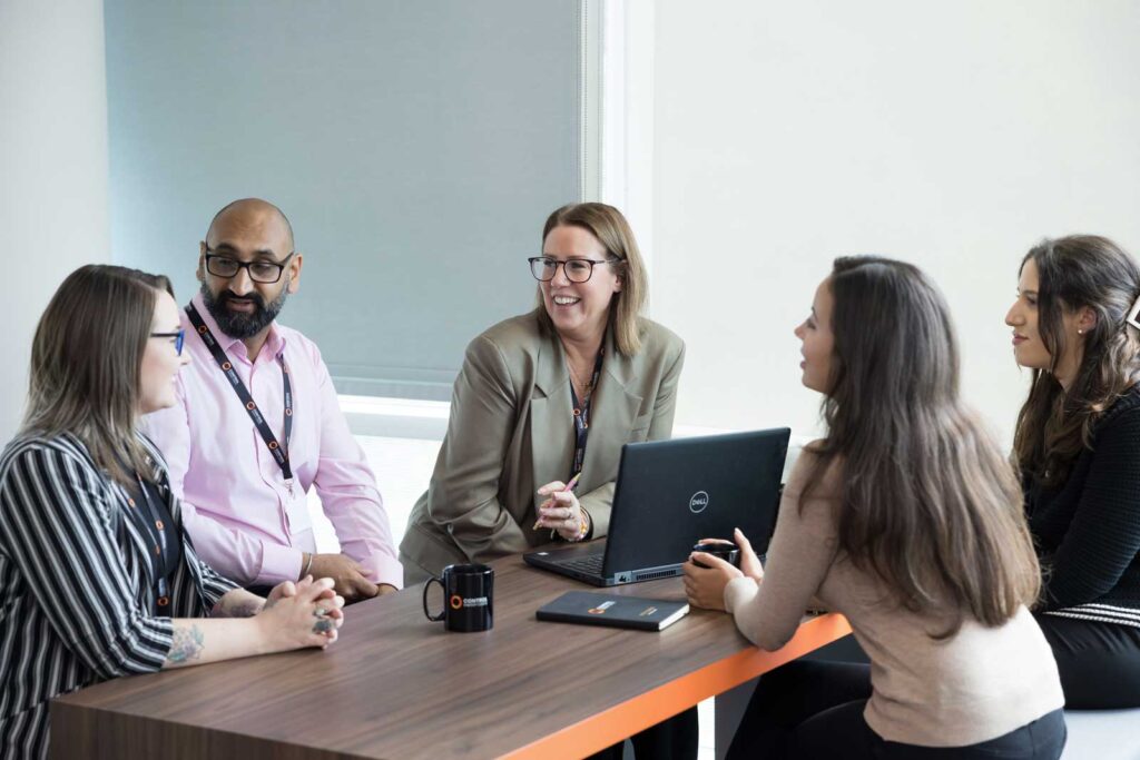 Corporate Office Lifestyle Photography - a team sitting around a table with an open laptop having a discussion