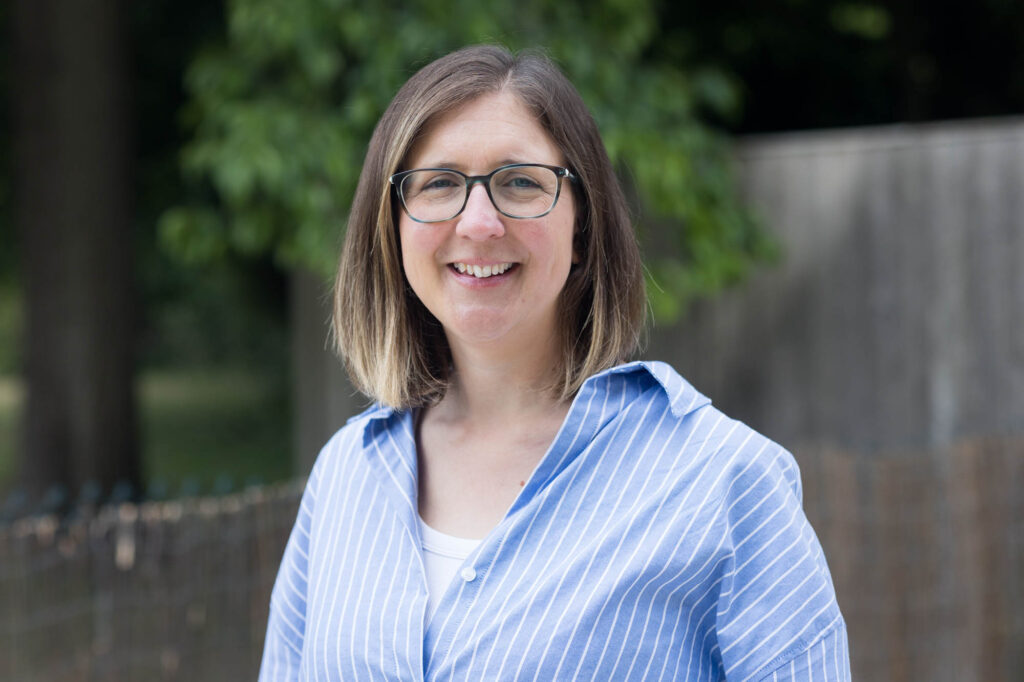 Professional headshot photography in Bromley - a business woman in a blue shirt stands in front of a tree