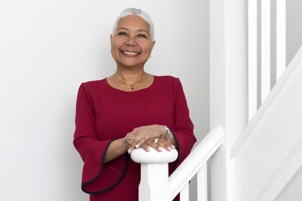 An example of what to wear for a professional headshot; a photo of a businesswoman standing on a staircase in a deep red top.