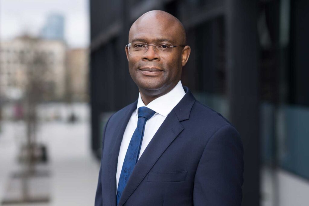 A businessman poses for his professional headshot in Ruskin Square in Croydon. He is wearing a dark blue suit & tie.