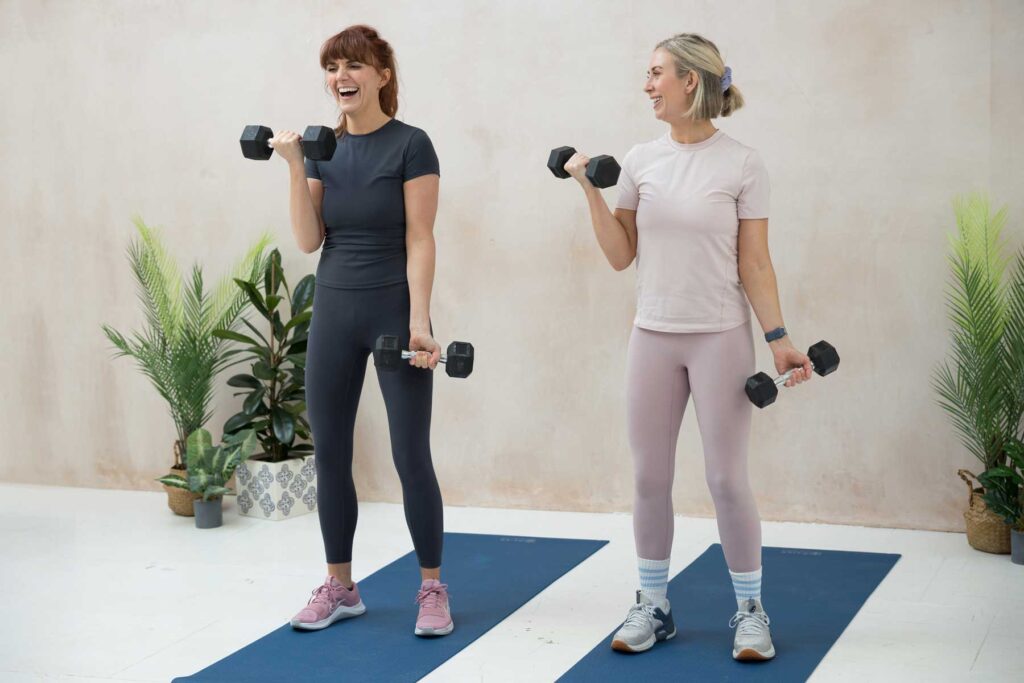 Fitness instructors laugh together whilst they are leading a class during a brand photography shoot