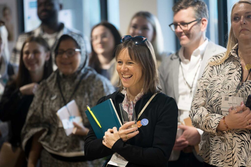 Photogrpahy of a woman laughing whilst listening to a speaker at a London business event.