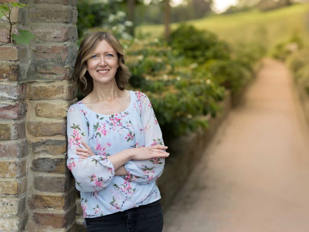 Personal branding photography a female business owner leans against a brick wall with the sunshine behind her